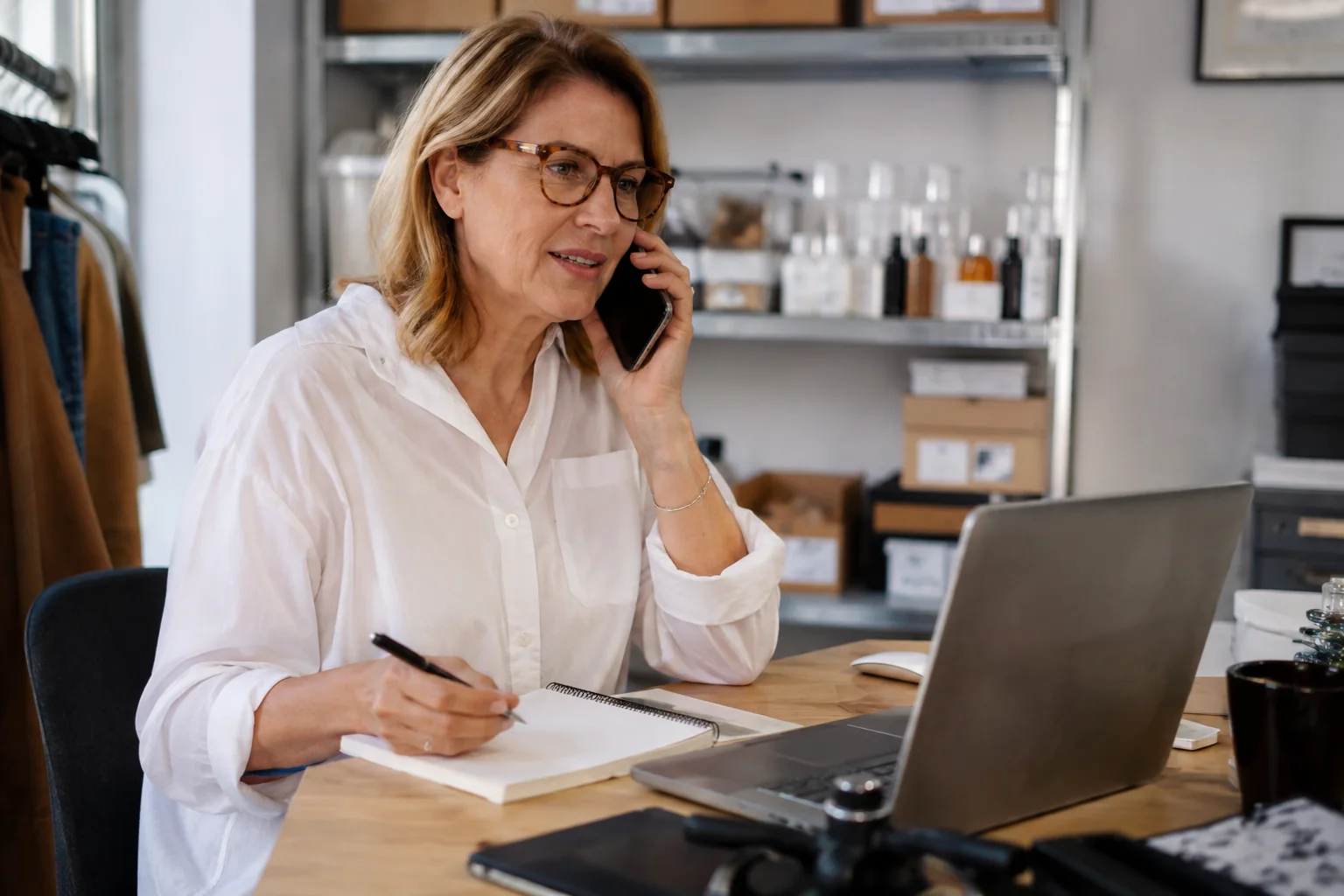 Business owner taking notes while discussing customer feedback by phone